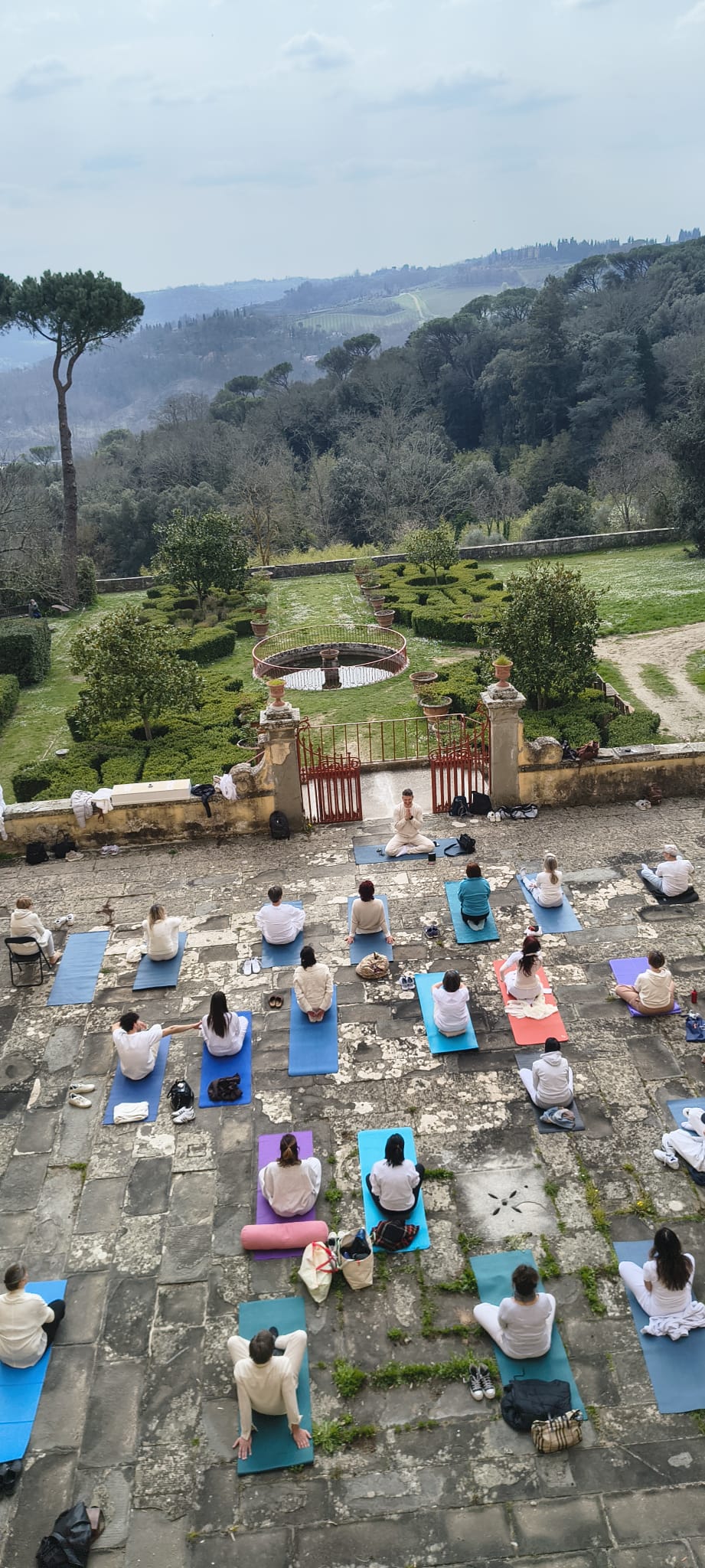 Meditazione di gruppo nel cortile di Villa Vrindavana, con vista sui giardini e sulle colline del Chianti