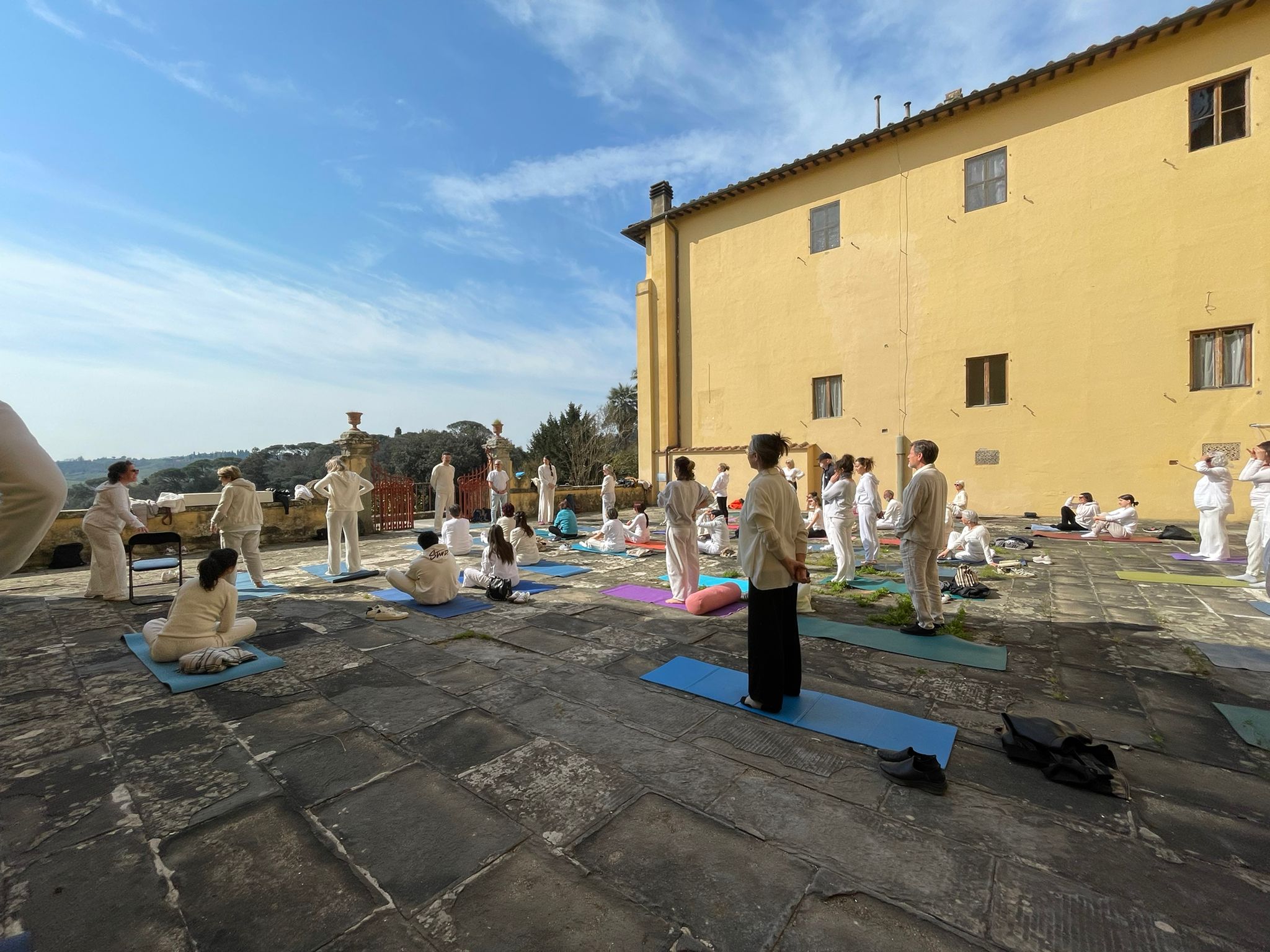 Pratica di gruppo all’aperto accanto agli edifici gialli di Villa Vrindavana